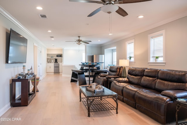 living room with ceiling fan, built in features, crown molding, and light wood-type flooring