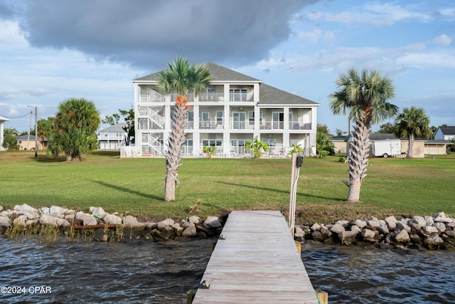 back of property featuring a balcony, a lawn, and a water view