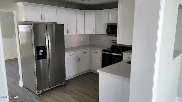 kitchen featuring stainless steel appliances, wood-type flooring, backsplash, and white cabinetry