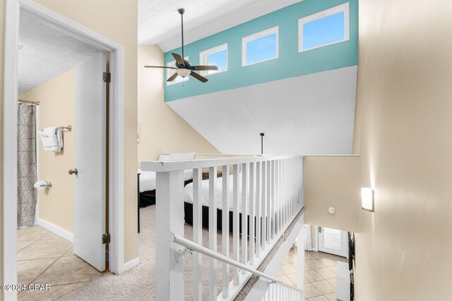 staircase with ceiling fan, tile patterned floors, a textured ceiling, and lofted ceiling