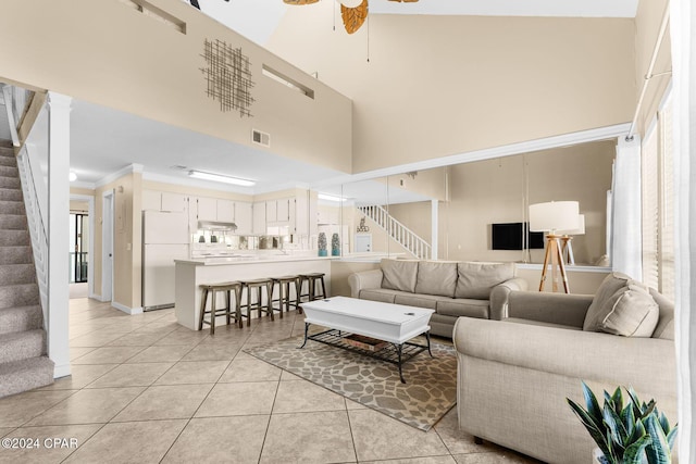 living room featuring crown molding, a towering ceiling, ceiling fan, and light tile patterned flooring