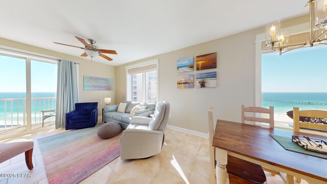 tiled living room featuring ceiling fan with notable chandelier and a water view