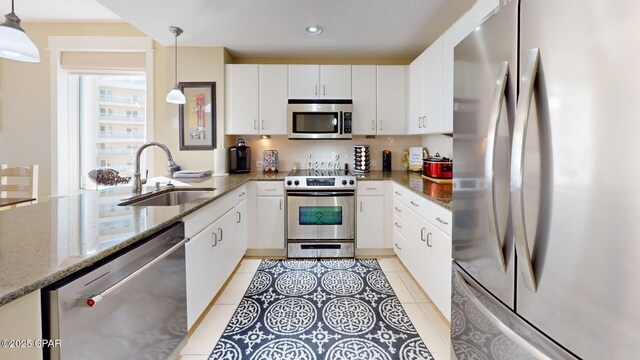 kitchen featuring sink, white cabinetry, stainless steel appliances, and hanging light fixtures