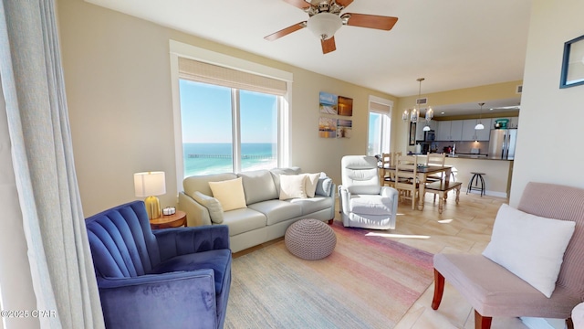 living room with ceiling fan with notable chandelier, light tile patterned flooring, and a water view