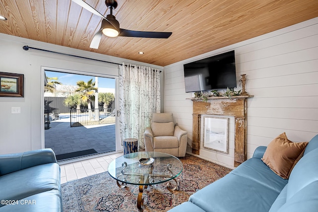 living room with a fireplace, ceiling fan, wooden ceiling, and wood walls