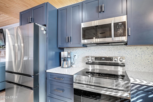 kitchen featuring light stone countertops, blue cabinetry, appliances with stainless steel finishes, and tasteful backsplash