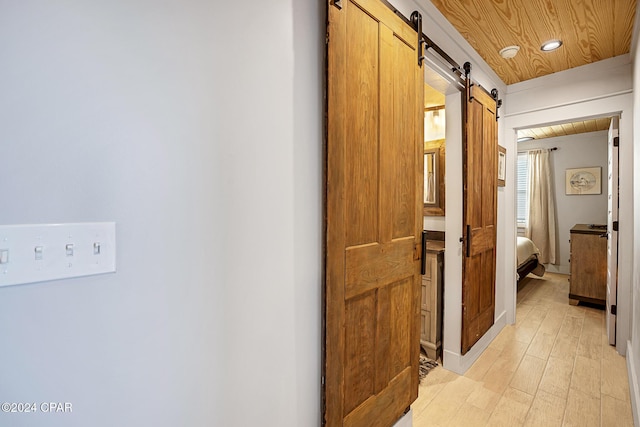 hallway featuring a barn door and light hardwood / wood-style flooring