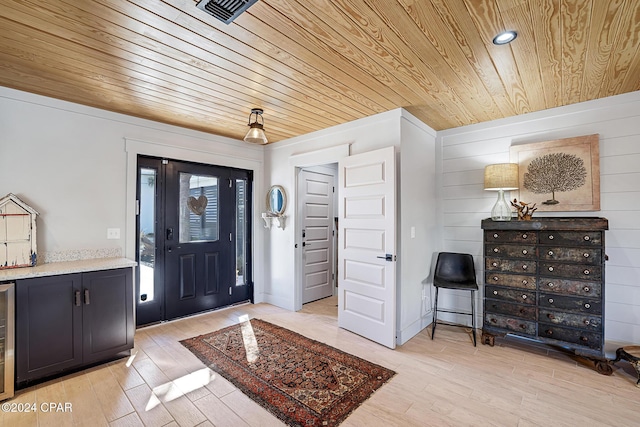 entrance foyer featuring wood walls, beverage cooler, wooden ceiling, and light wood-type flooring