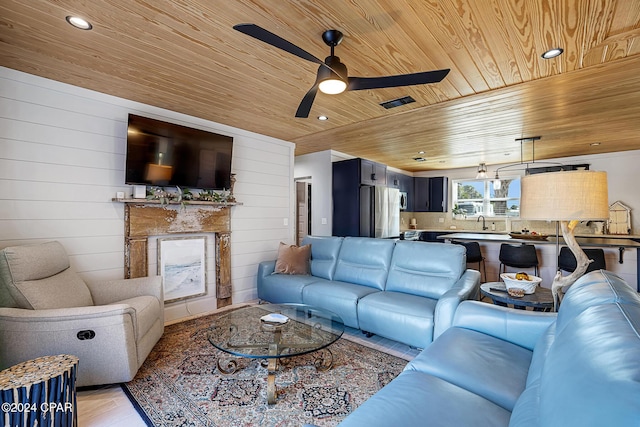 living room with sink, ceiling fan, wooden ceiling, and wood walls