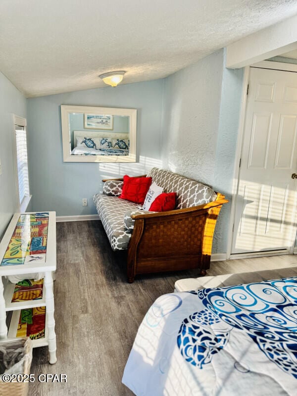 bedroom with hardwood / wood-style flooring, a textured ceiling, and vaulted ceiling