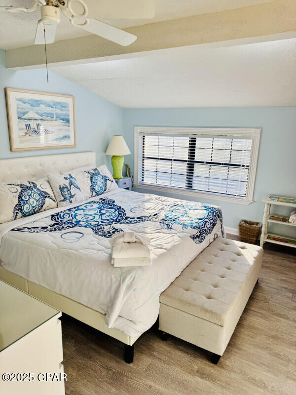 bedroom with hardwood / wood-style floors, ceiling fan, and lofted ceiling with beams