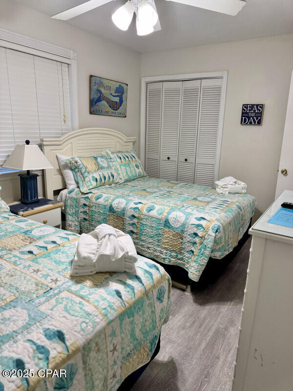 bedroom with ceiling fan, a closet, and wood-type flooring