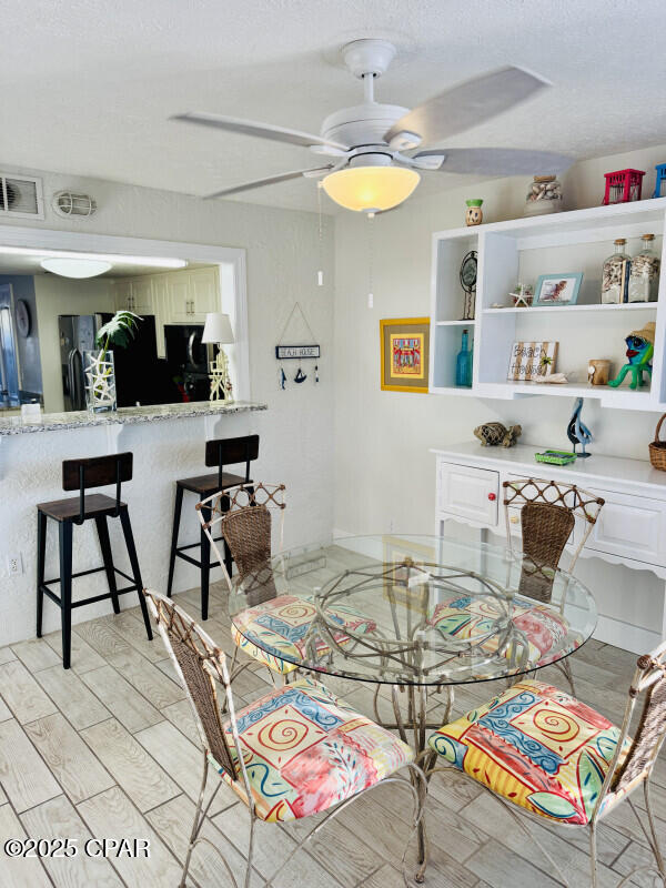 dining room featuring a textured ceiling, light hardwood / wood-style flooring, and ceiling fan