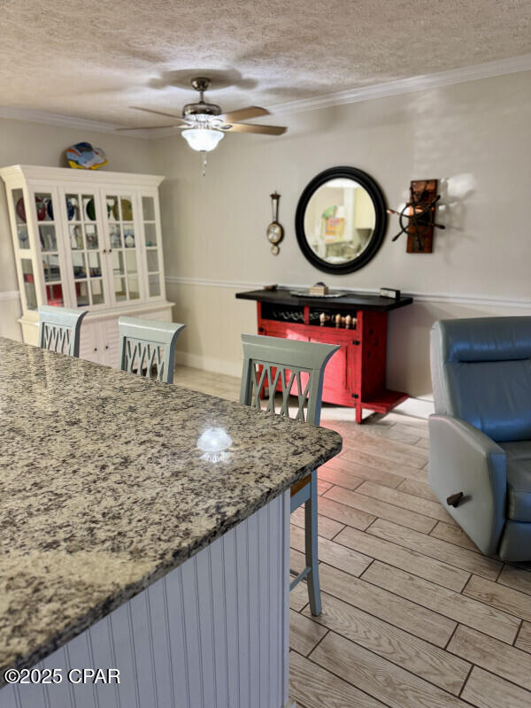 dining space featuring ceiling fan, crown molding, and a textured ceiling