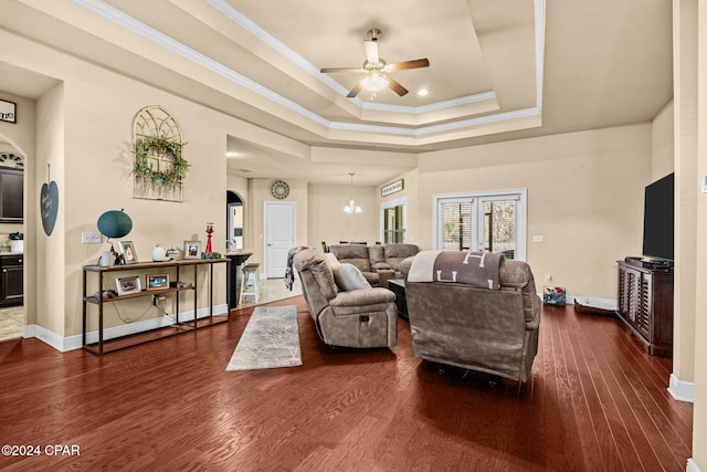 living room with ceiling fan, wood-type flooring, ornamental molding, and a tray ceiling