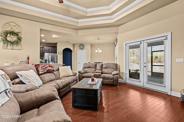 living room with a raised ceiling, crown molding, a chandelier, and dark hardwood / wood-style floors