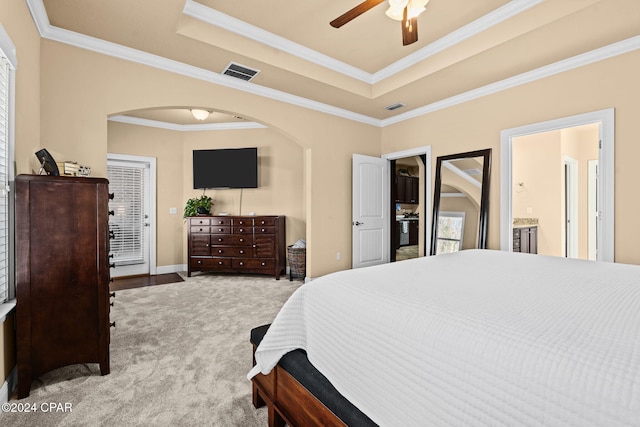 bedroom featuring a raised ceiling, ensuite bath, ceiling fan, access to exterior, and ornamental molding