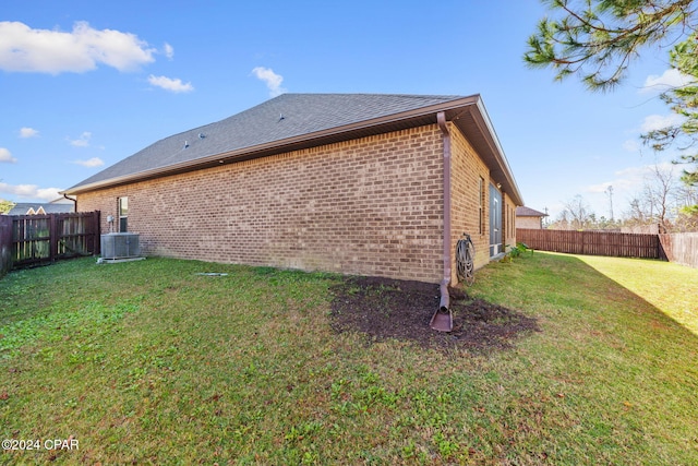 view of side of home featuring central AC and a yard