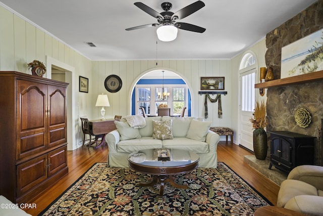 living room with ceiling fan with notable chandelier, dark hardwood / wood-style floors, and a wood stove