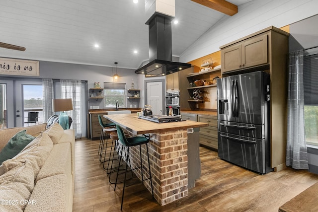 kitchen with wooden counters, island range hood, lofted ceiling with beams, hanging light fixtures, and appliances with stainless steel finishes