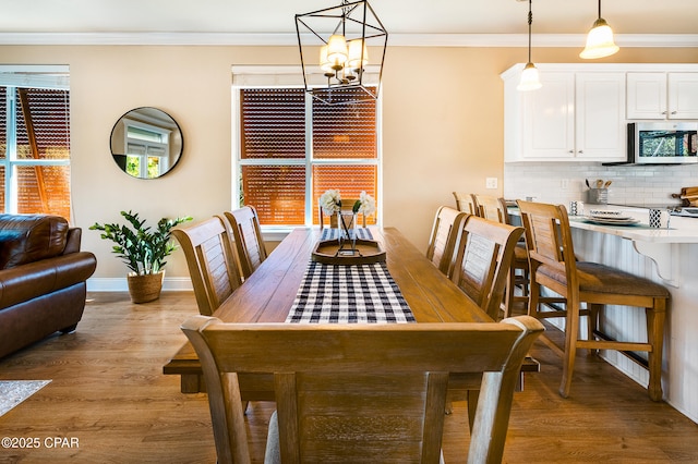 dining space featuring light hardwood / wood-style floors, an inviting chandelier, and ornamental molding