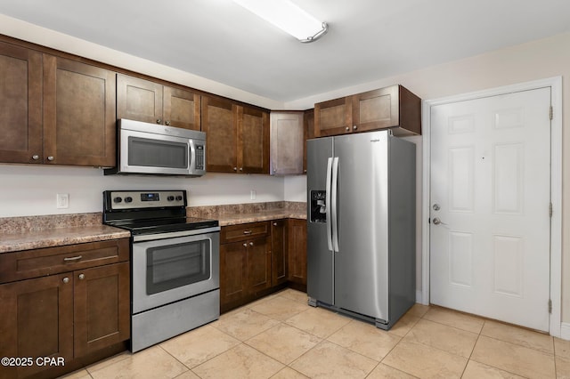 kitchen with stone counters, appliances with stainless steel finishes, dark brown cabinetry, and light tile patterned floors