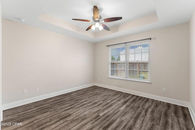 spare room with ceiling fan, dark hardwood / wood-style flooring, and a tray ceiling