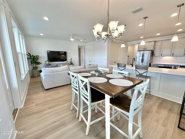 unfurnished living room featuring ceiling fan with notable chandelier and light hardwood / wood-style floors