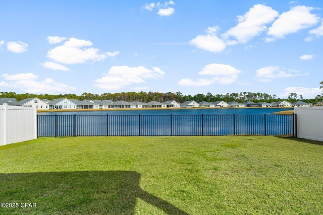 rear view of house with a water view and a lawn