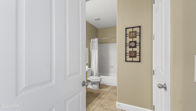 bathroom featuring toilet, a textured ceiling, tile patterned floors, and shower / bathtub combination with curtain