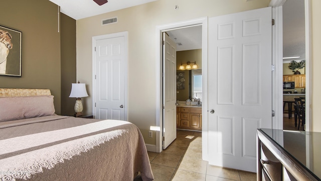 bedroom featuring light tile patterned floors, connected bathroom, and ceiling fan