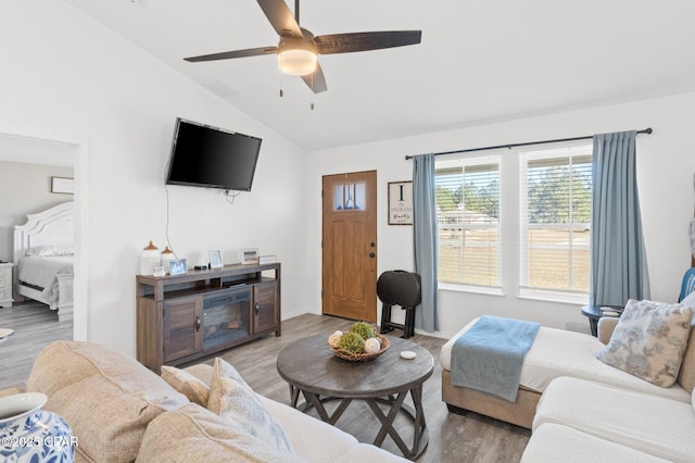 living room featuring ceiling fan, wood-type flooring, and vaulted ceiling