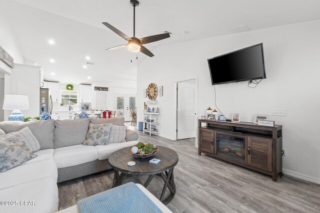 living room featuring ceiling fan, light hardwood / wood-style floors, french doors, and vaulted ceiling