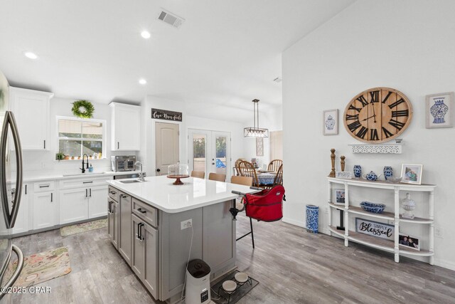 kitchen featuring white cabinets, decorative light fixtures, a kitchen island, and light hardwood / wood-style floors