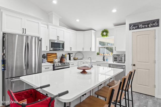 kitchen with a kitchen breakfast bar, a kitchen island, stainless steel appliances, and vaulted ceiling