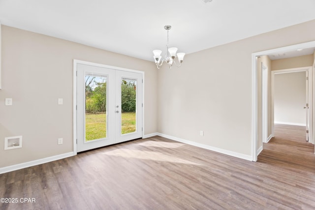 empty room featuring hardwood / wood-style floors, french doors, and a notable chandelier