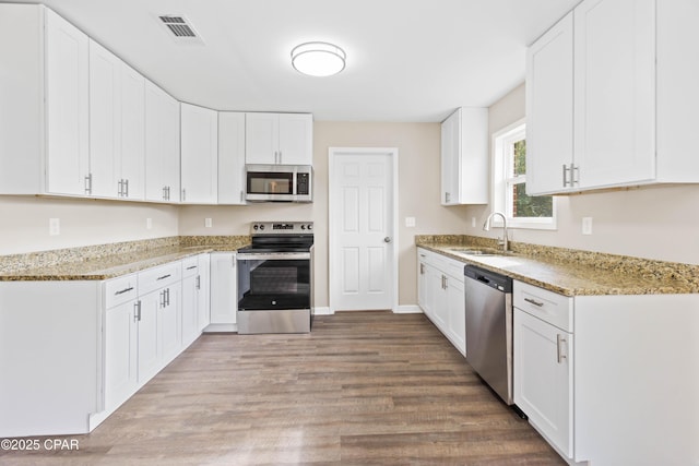 kitchen featuring white cabinets, sink, light stone countertops, light wood-type flooring, and stainless steel appliances