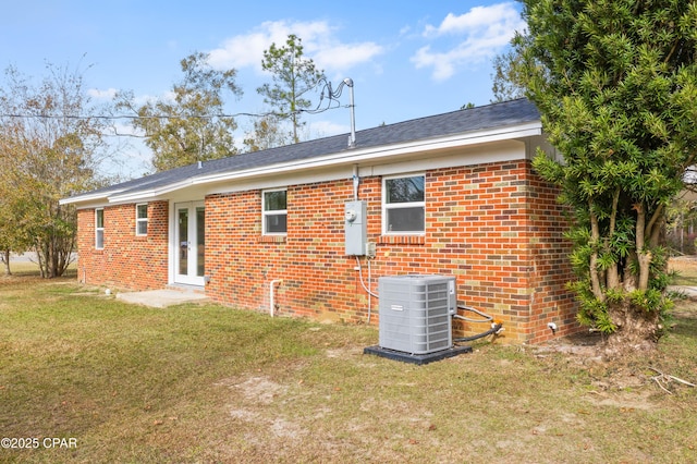 rear view of property with a lawn and cooling unit