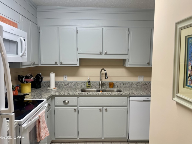 kitchen featuring white cabinets, light stone countertops, white appliances, and sink