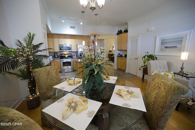 dining space featuring light wood-type flooring, a notable chandelier, and crown molding