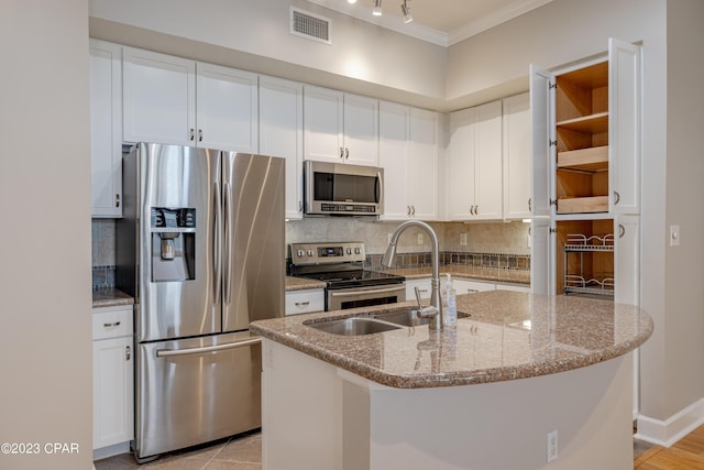 kitchen with white cabinets, light stone counters, an island with sink, and appliances with stainless steel finishes