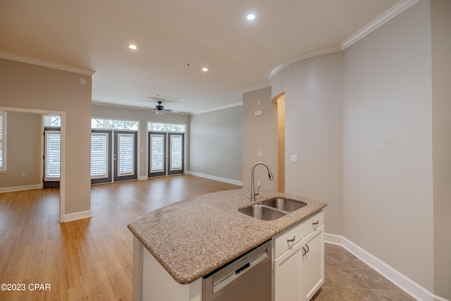 kitchen with ceiling fan, a kitchen island with sink, sink, dishwasher, and white cabinetry