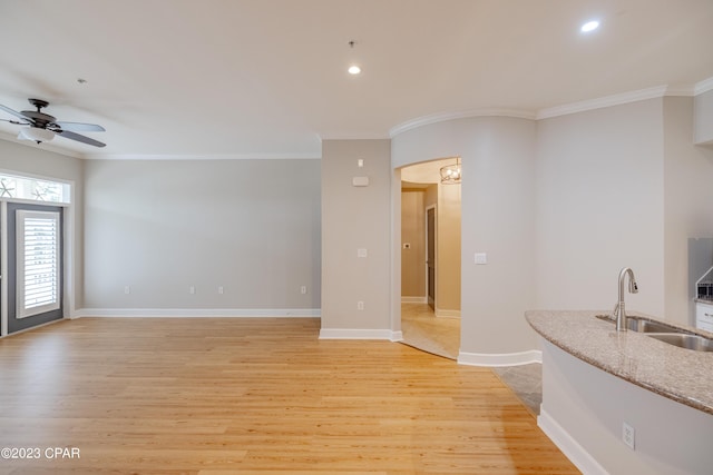 unfurnished living room with ceiling fan, ornamental molding, sink, and light hardwood / wood-style flooring