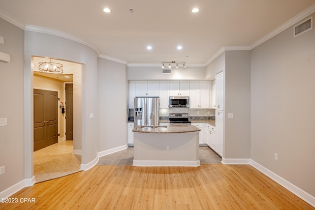 kitchen with backsplash, a kitchen island with sink, light hardwood / wood-style flooring, white cabinetry, and stainless steel appliances