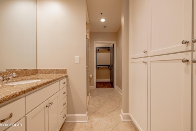 bathroom with a shower with door, vanity, and tile patterned flooring