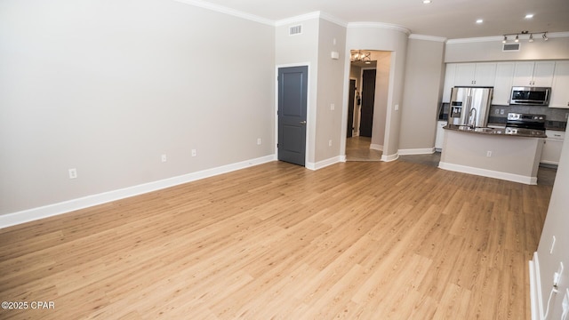 unfurnished living room featuring sink, light hardwood / wood-style flooring, ornamental molding, and a notable chandelier