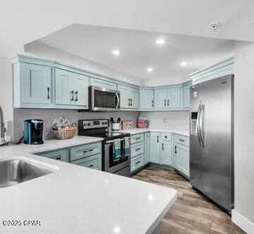 kitchen featuring hardwood / wood-style flooring, kitchen peninsula, sink, and appliances with stainless steel finishes