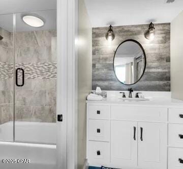 bathroom featuring combined bath / shower with glass door and vanity