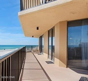 balcony with a water view and a view of the beach