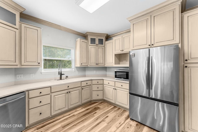 kitchen with ornamental molding, sink, stainless steel appliances, and light hardwood / wood-style flooring